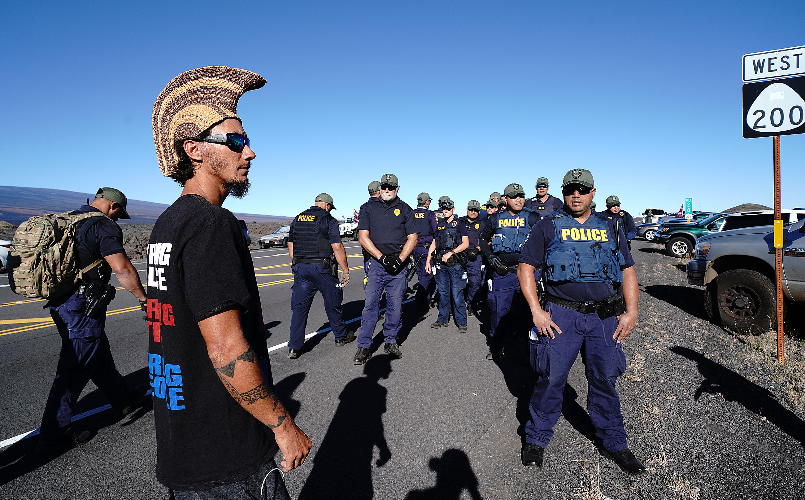 Kahoʻokahi Kanuha and Hawaiʻi County Sheriff's Officers at the Mauna Kea Summit Access Road. July 15, 2019. Photograph by Cory Lum.
